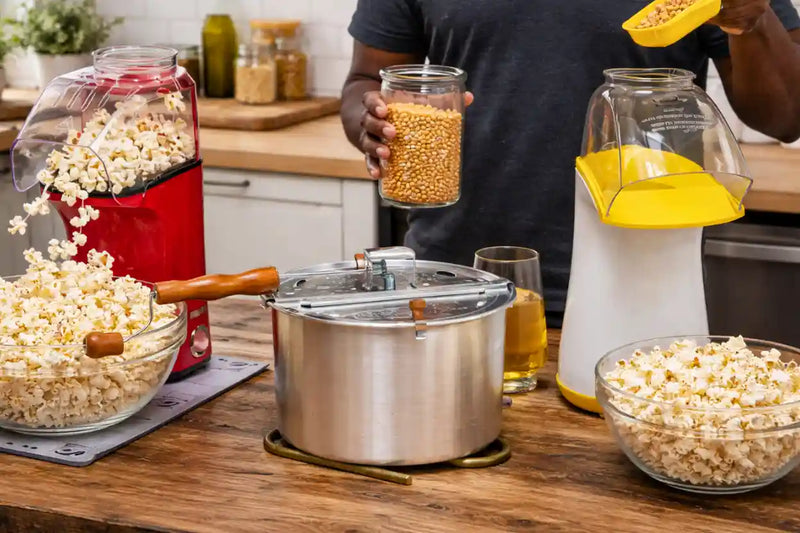 Best popcorn poppers with red popcorn machine, glass jars, and bowls of popcorn on a wooden table.