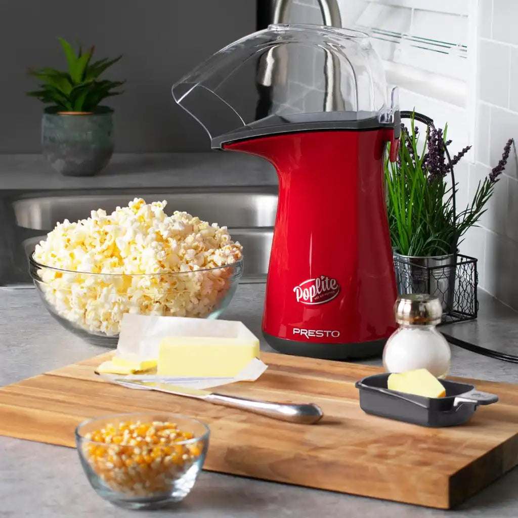 Red PopLite Presto popcorn maker on a kitchen counter with ingredients and a bowl of popcorn.